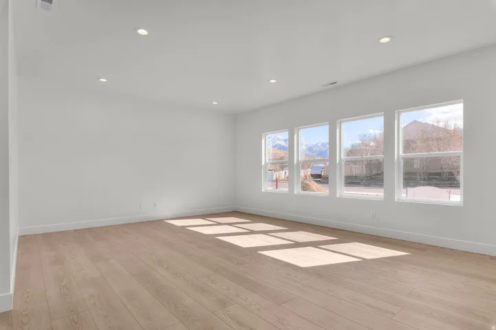 Recessed ceiling lighting, light wood-finish flooring, and multiple large windows
