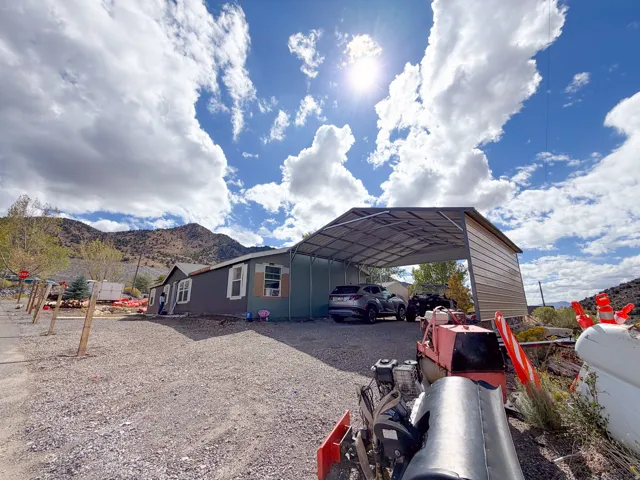 Detached structure with covered parking, gravel landscaping, and mountain backdrop