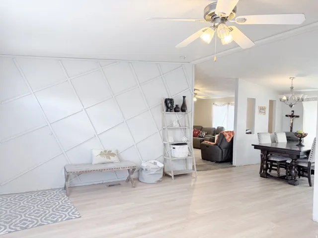 Diagonal wainscoting wall feature, light wood-finish flooring, and ceiling fan with integrated lighting