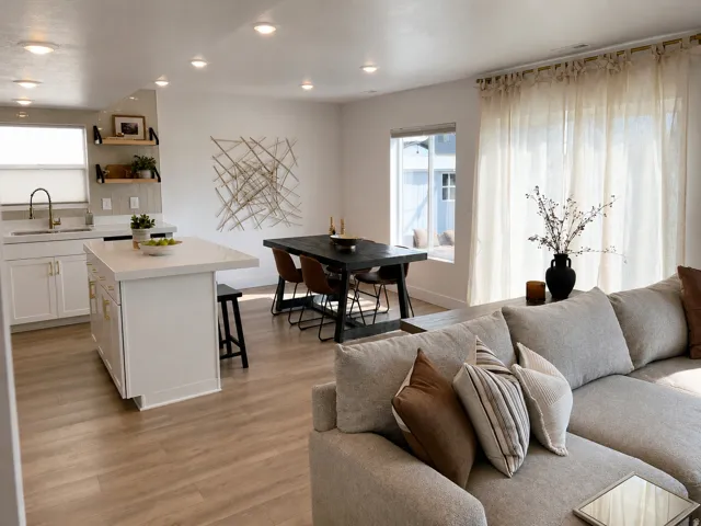 Recessed lighting, wood-finish flooring, white kitchen cabinetry with gold-tone hardware, kitchen island with countertop, and sliding glass door with curtains