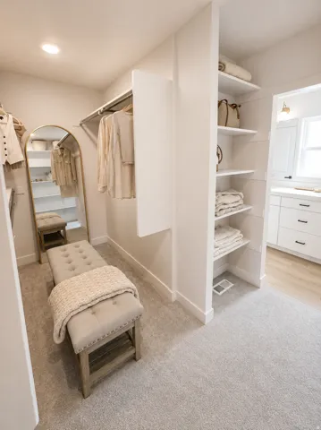 Recessed lighting, built-in shelving, hanging closet rods, light-toned carpeting, and light wood-finish flooring
