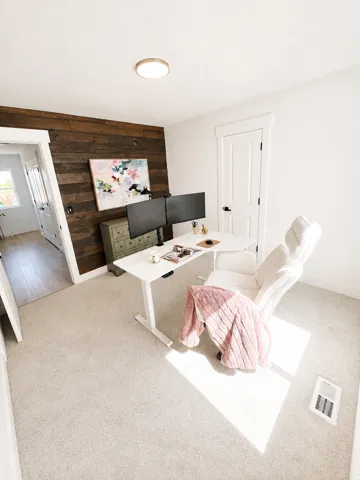 Carpeted flooring, white interior doors, and a wood-paneled accent wall
