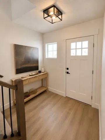Entryway featuring a white paneled door with glass inserts, wood-finish flooring, a contemporary ceiling light fixture, and a window for natural light