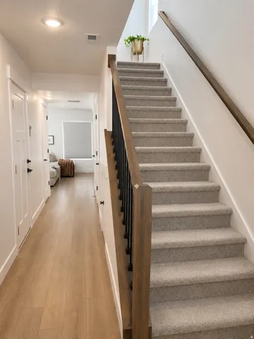 Light wood-finish flooring extending through a hallway with recessed lighting