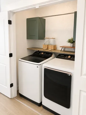 Dedicated laundry area featuring a wood-finish shelf, single upper cabinet, and a chrome hanging rod