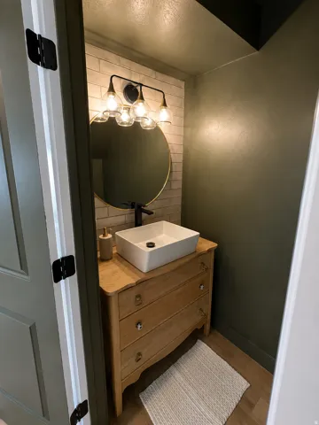 Modern vanity featuring a vessel sink, a wall-mounted faucet, and a circular mirror
