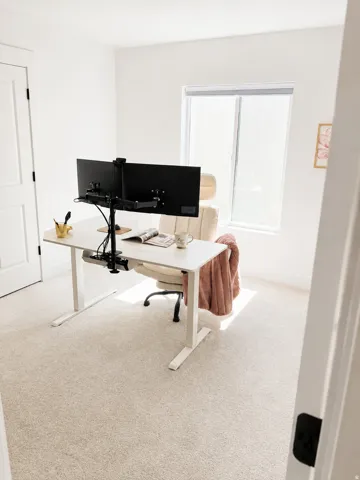 White door with dark hardware, light-colored carpeting, and a window with blinds