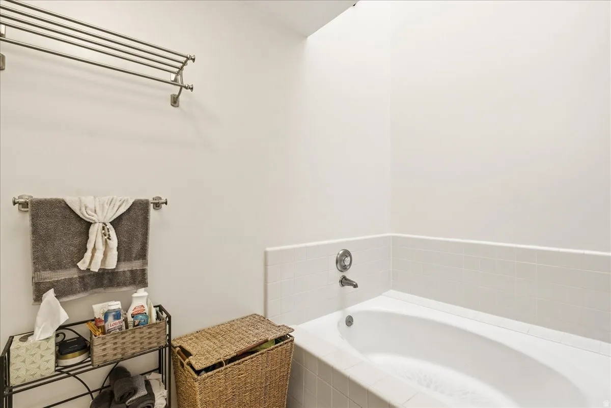 White soaking tub with tiled surround and chrome fixtures