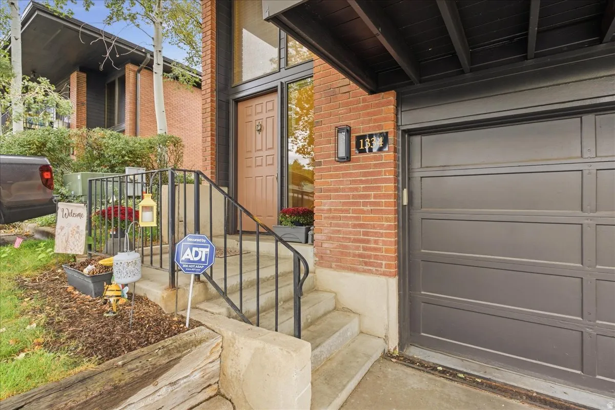 Brick exterior with an attached garage, concrete steps, and a wrought iron handrail leading to the entrance