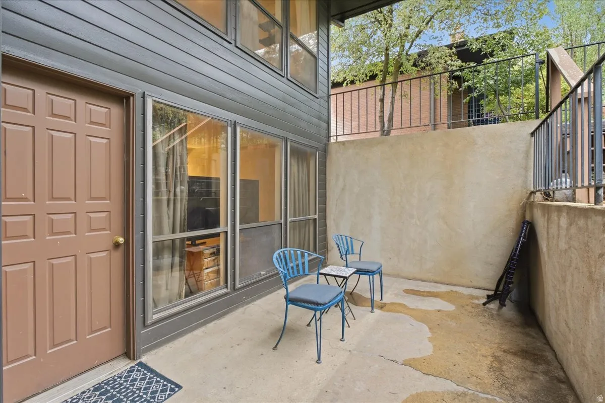 Private patio area featuring a concrete surface, stucco wall, and metal railing
