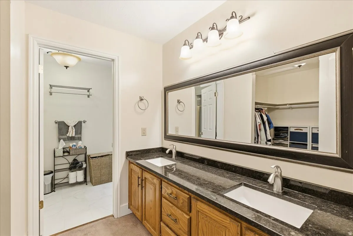Double vanity with dark countertops and wood-finish cabinetry
