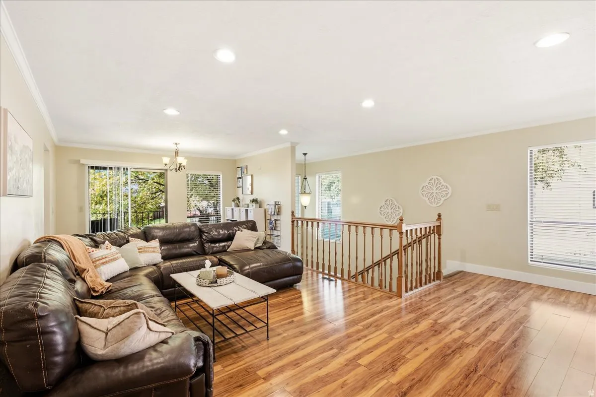Wood-finish flooring, recessed lighting, crown molding, a sliding glass door, and a spindle staircase