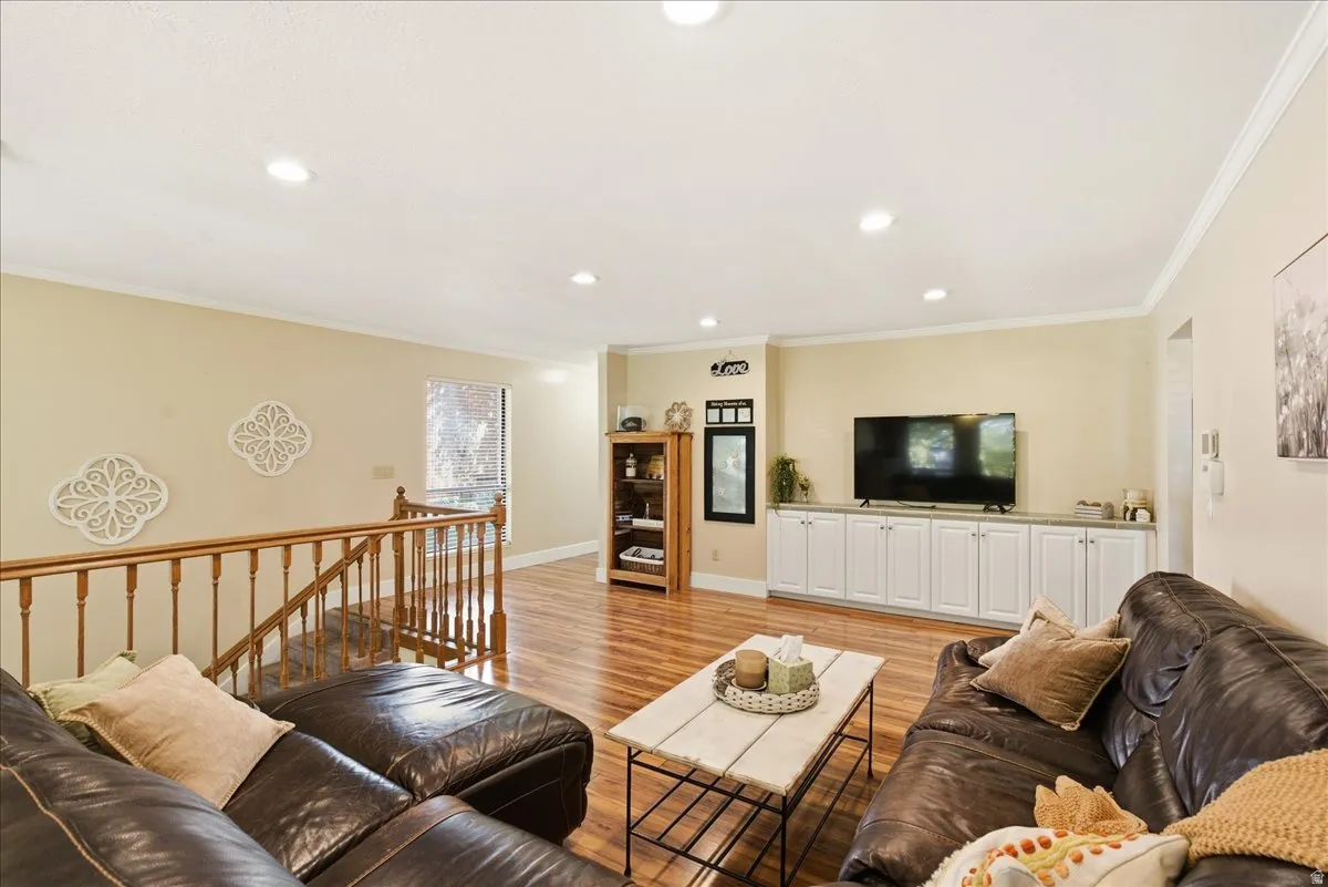 Recessed lighting, wood-finish flooring, white built-in cabinetry, and wood staircase railing