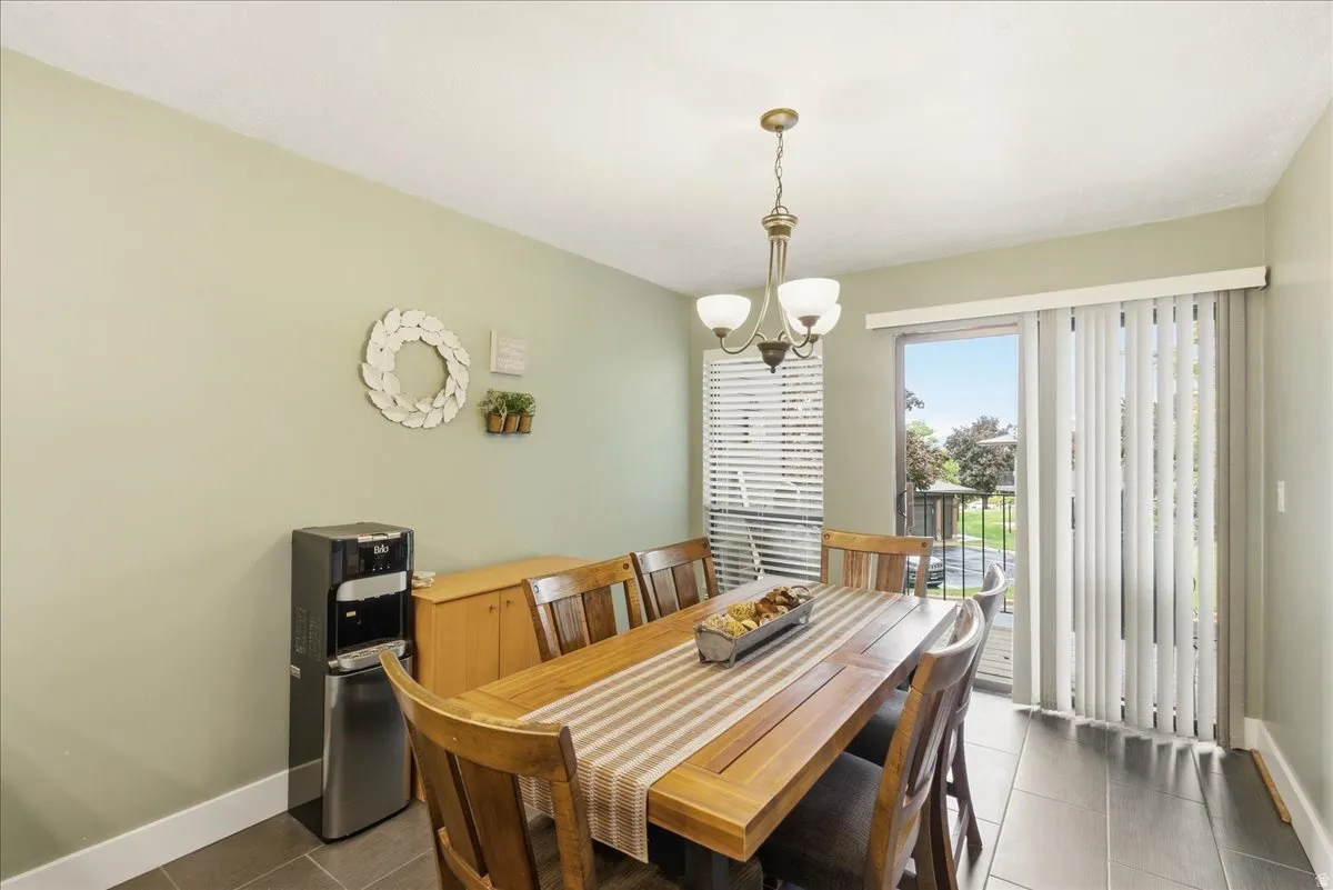 Recessed lighting, sliding glass door with vertical blinds, tile flooring, and a decorative chandelier