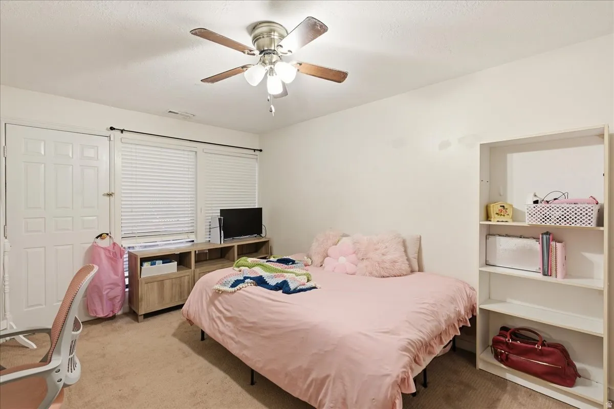 Ceiling fan with light fixture, window with blinds, wood-finish media console, built-in shelving, panel door