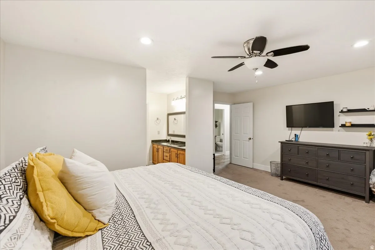 Recessed lighting, ceiling fan, wood-finish vanity with countertop, framed mirror, and wall-mounted shelving