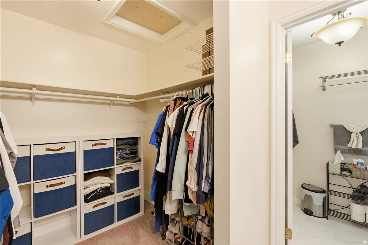 Built-in shelving units, multiple clothing rods, overhead wire shelving, and an attic access panel