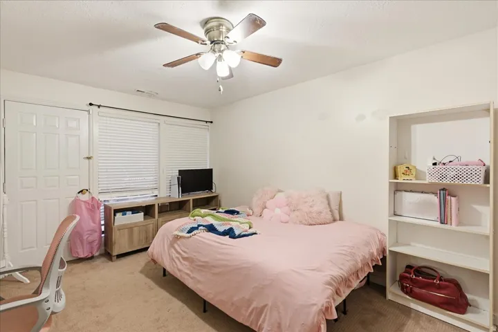 Ceiling fan with light fixture, window with blinds, wood-finish media console, built-in shelving, panel door