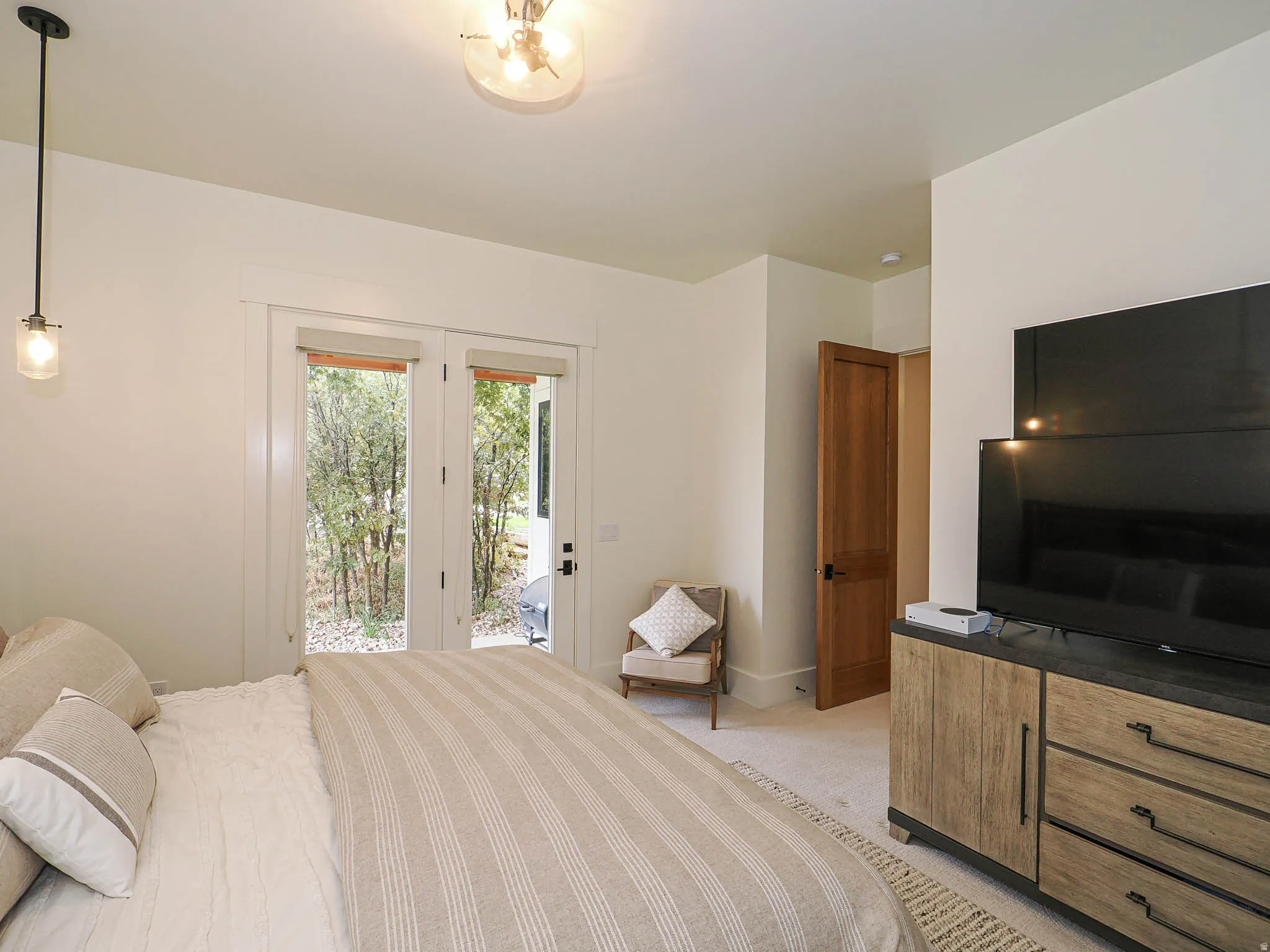 White walls with french doors, a built-in wood-finish dresser, a flush-mount ceiling light fixture, and a pendant light fixture
