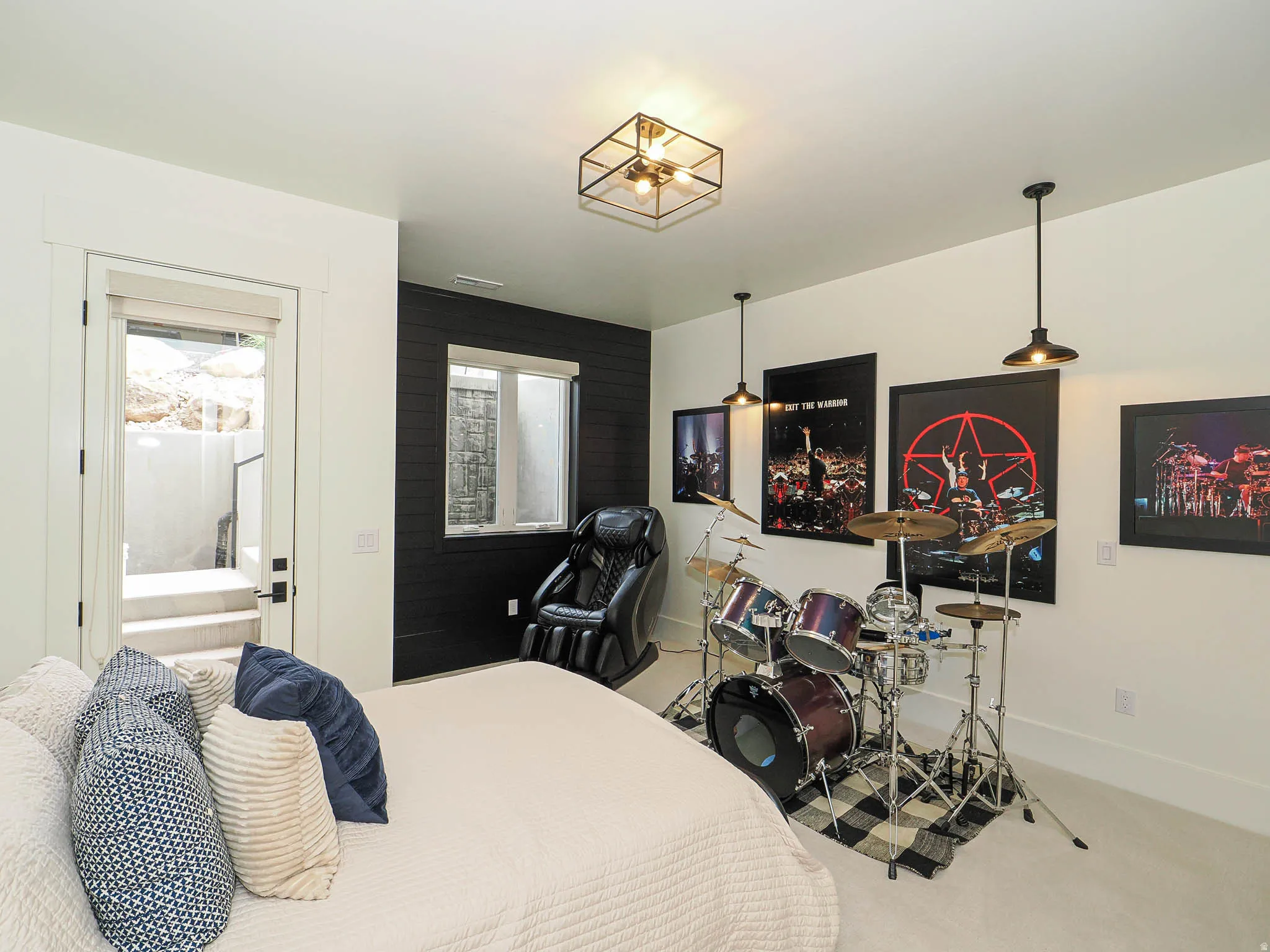 White walls with a black accent wall, ceiling-mounted light fixture, two pendant light fixtures, a window, and a door leading to exterior stairs