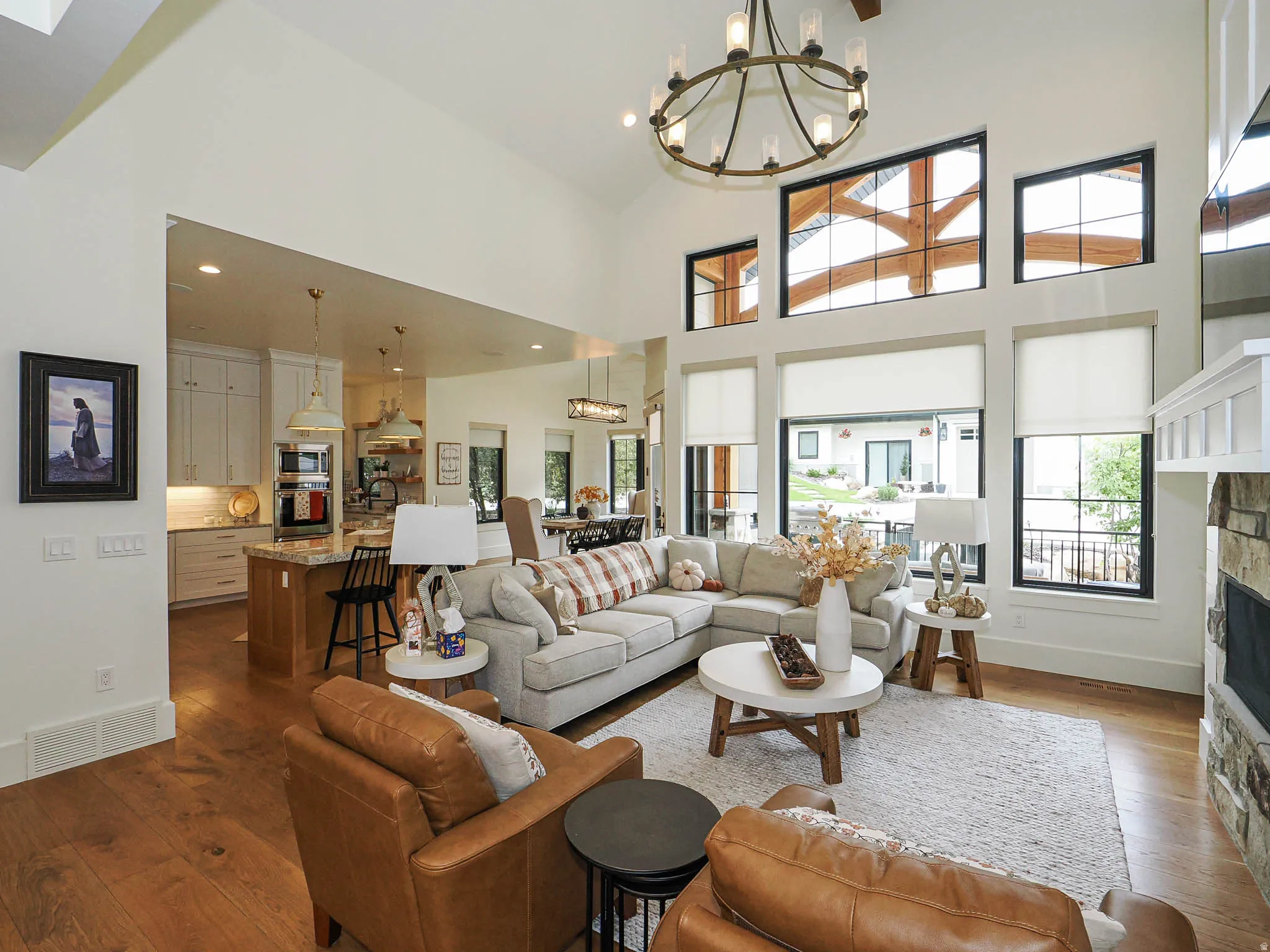 Expansive great room featuring a soaring ceiling, wood-finish flooring, and a stone-clad fireplace