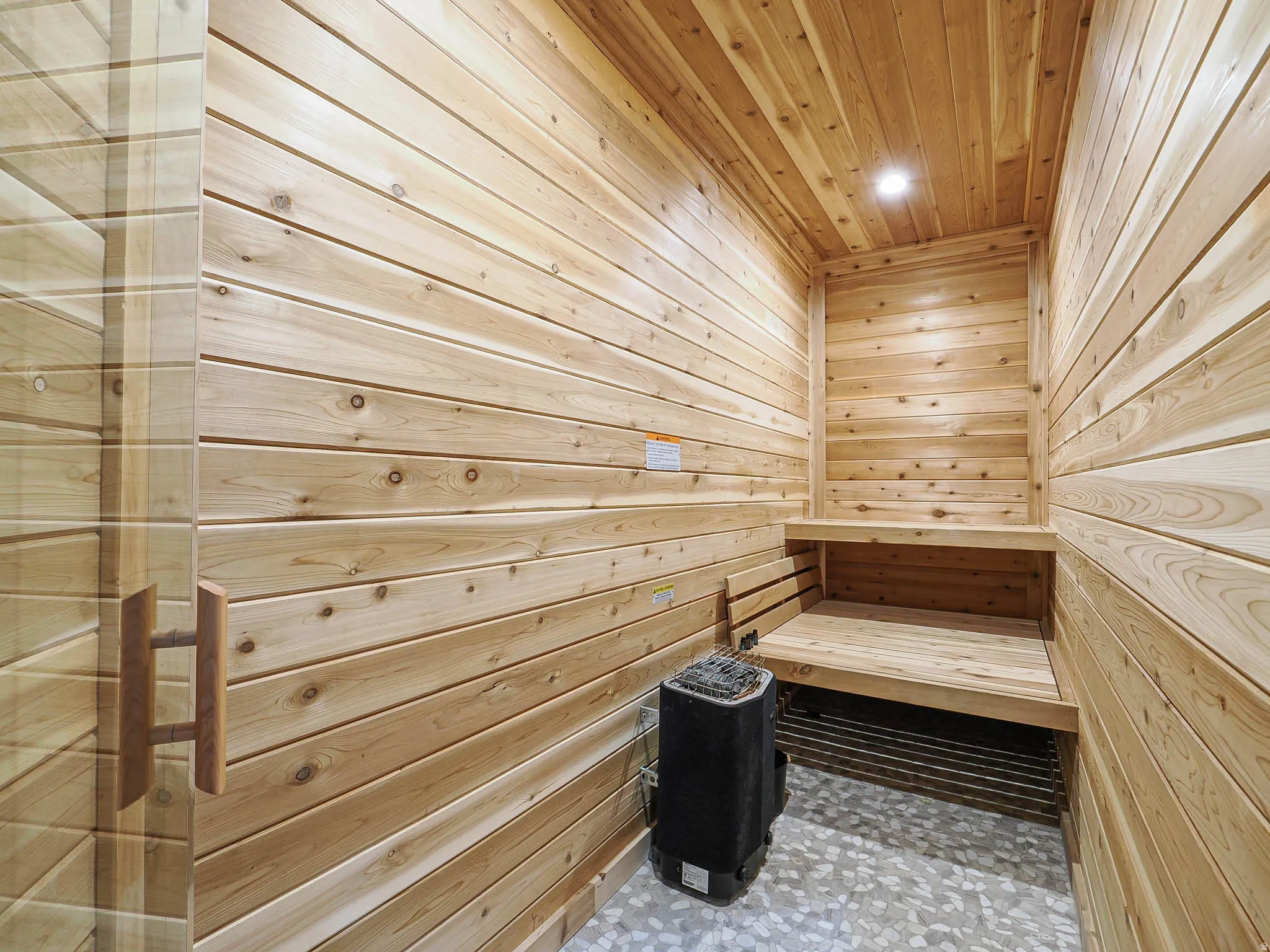 Built-in sauna with light wood paneling, integrated wood benches, and a visible heating unit