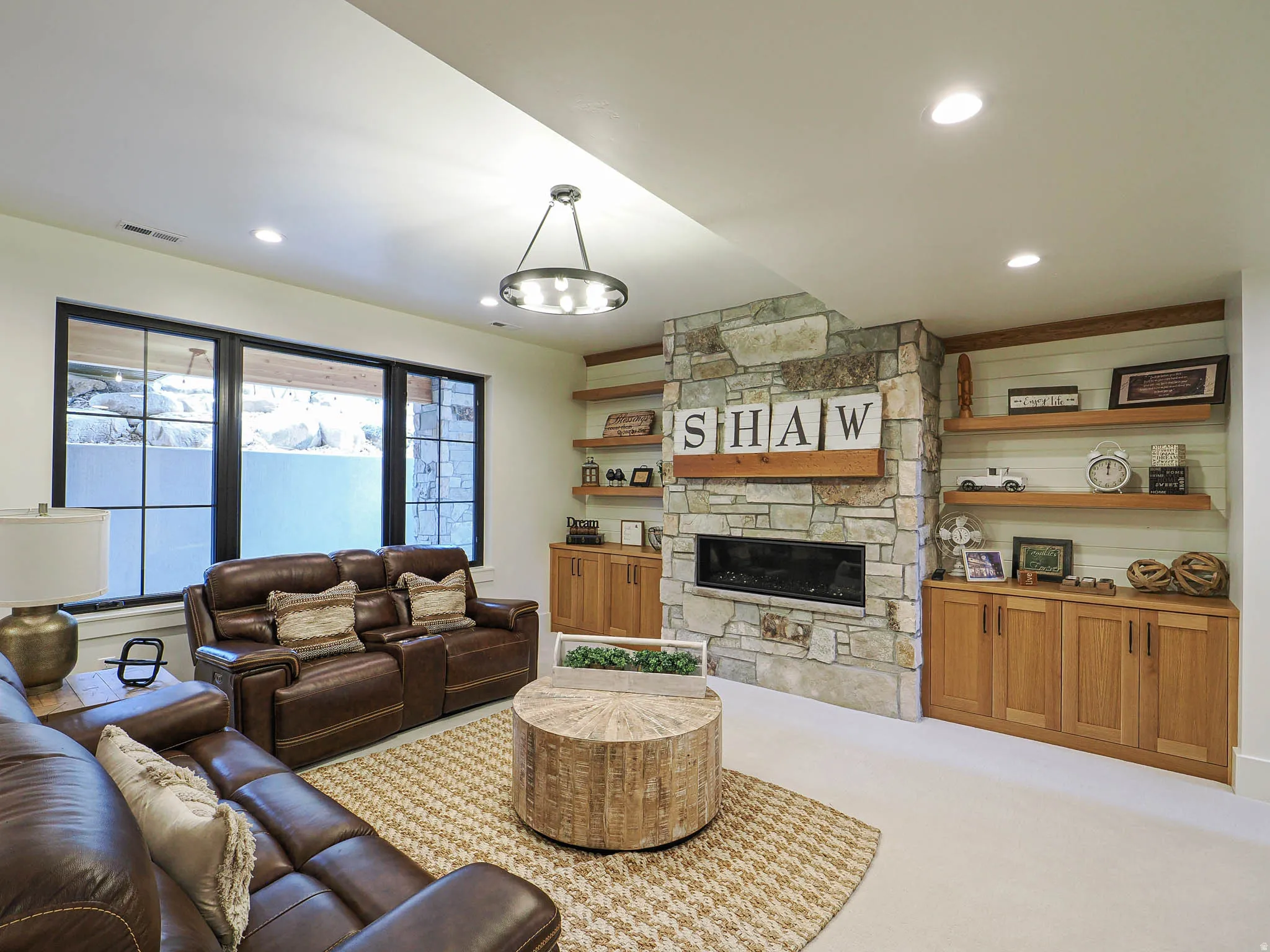 Built-in stone fireplace with an integrated linear insert, custom wood shelving, recessed lighting, and large egress windows