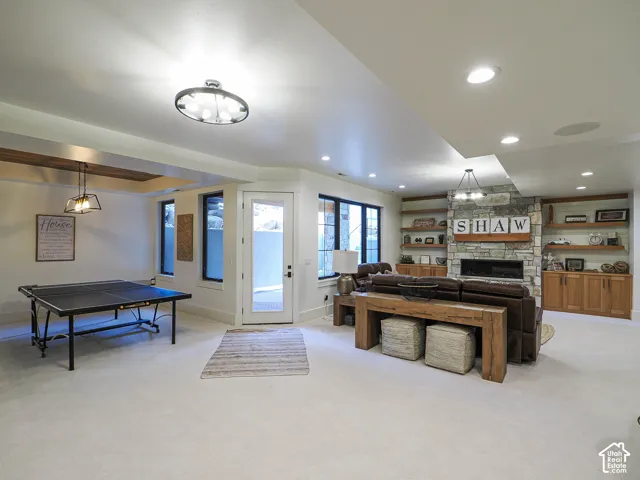 Recessed lighting, stone-clad fireplace, integrated shelving, built-in cabinetry, and a glass-paneled door