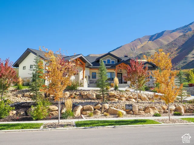 Stone facade residence featuring a prominent entryway, multi-level architectural design, and integrated landscaping with natural rock elements