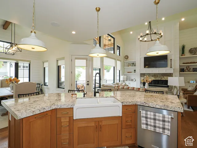 Kitchen island featuring a farmhouse sink, granite countertops, and light wood cabinetry
