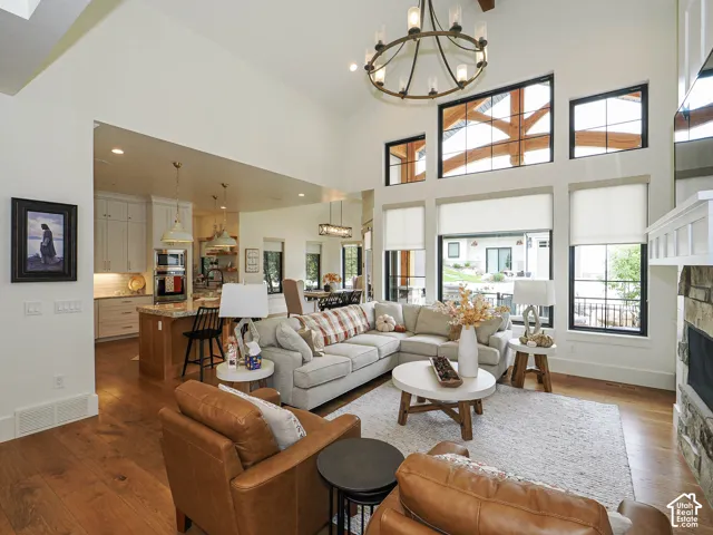 Expansive great room featuring a soaring ceiling, wood-finish flooring, and a stone-clad fireplace