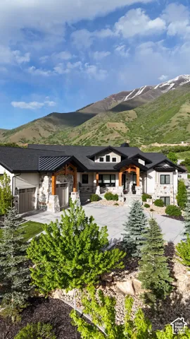 Contemporary architecture featuring stone and stucco finishes, exposed wood beams, a multi-car garage, and a concrete driveway