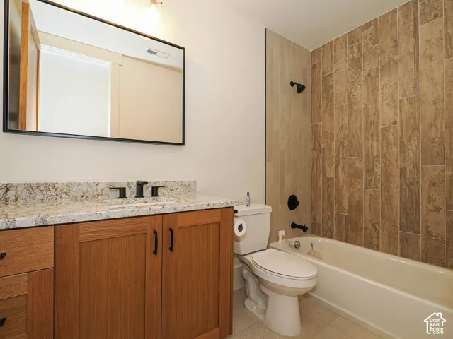 Bathroom featuring a single vanity with stone countertop, wood-finish cabinetry, and matte black fixtures