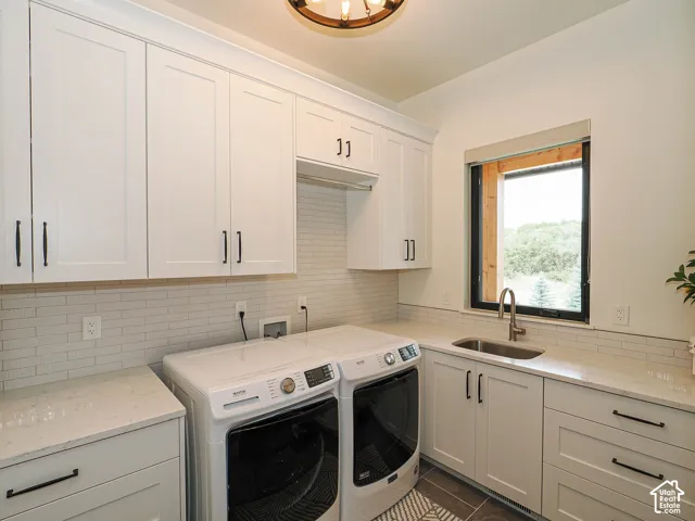 White shaker-style cabinetry with matte black hardware, light quartz countertops, a subway tile backsplash, a stainless steel sink with a gooseneck faucet, and a large window with black trim