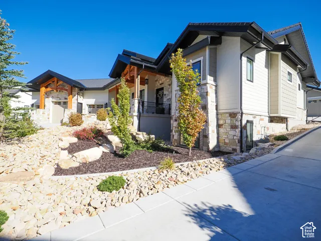Contemporary home with stone and siding exterior, a dark shingle roof, and a concrete driveway