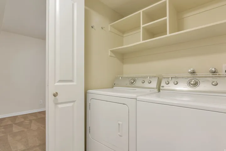 Dedicated laundry area with built-in shelving, a full-size washer, and a full-size dryer