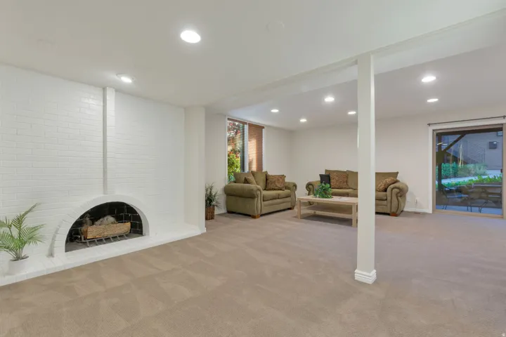 Expansive room featuring a white brick fireplace with an arched opening, recessed lighting, and light-toned carpeting
