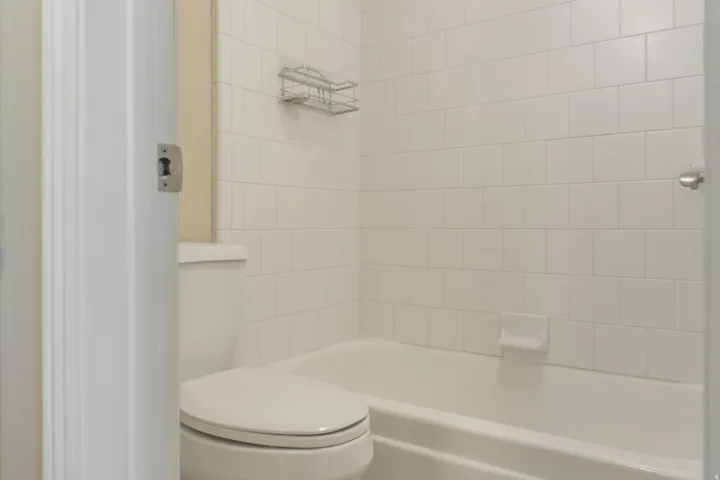 White tiled shower surround with an integrated bathtub