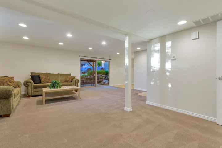 Recessed lighting illuminates the carpeted living area with a support column and a sliding glass door