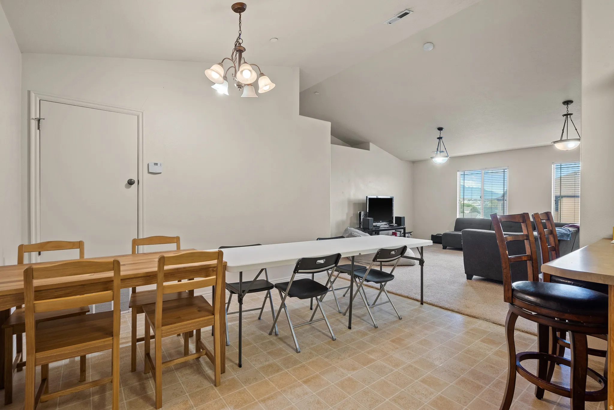Vaulted ceilings with pendant lighting, tile flooring, and a door with hardware
