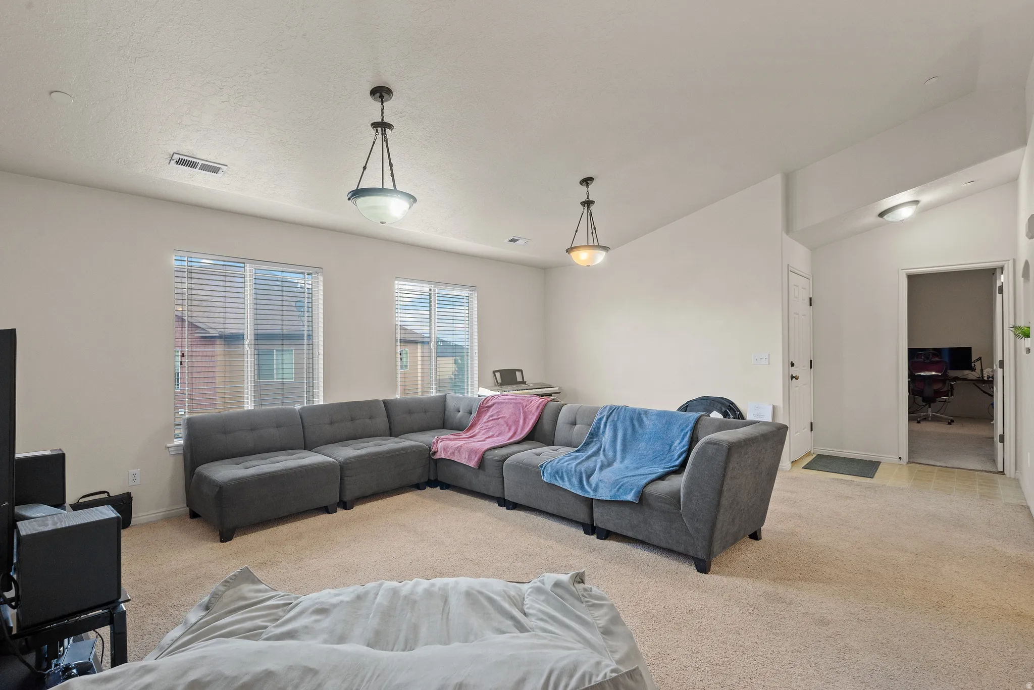 Vaulted ceiling, two windows with blinds, recessed lighting, and pendant light fixtures