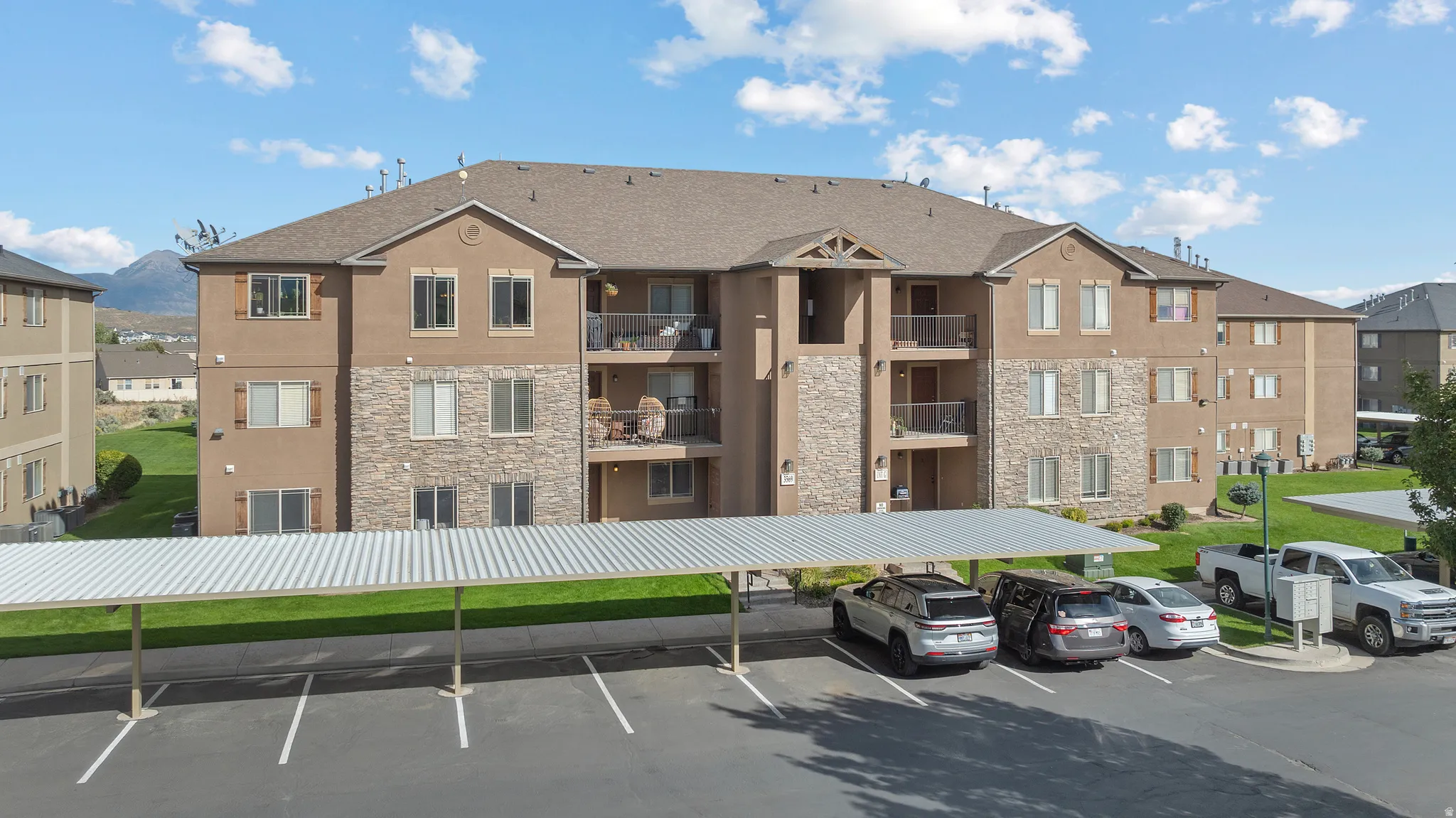 Multi-story building featuring balconies, stone veneer accents, and exterior lighting