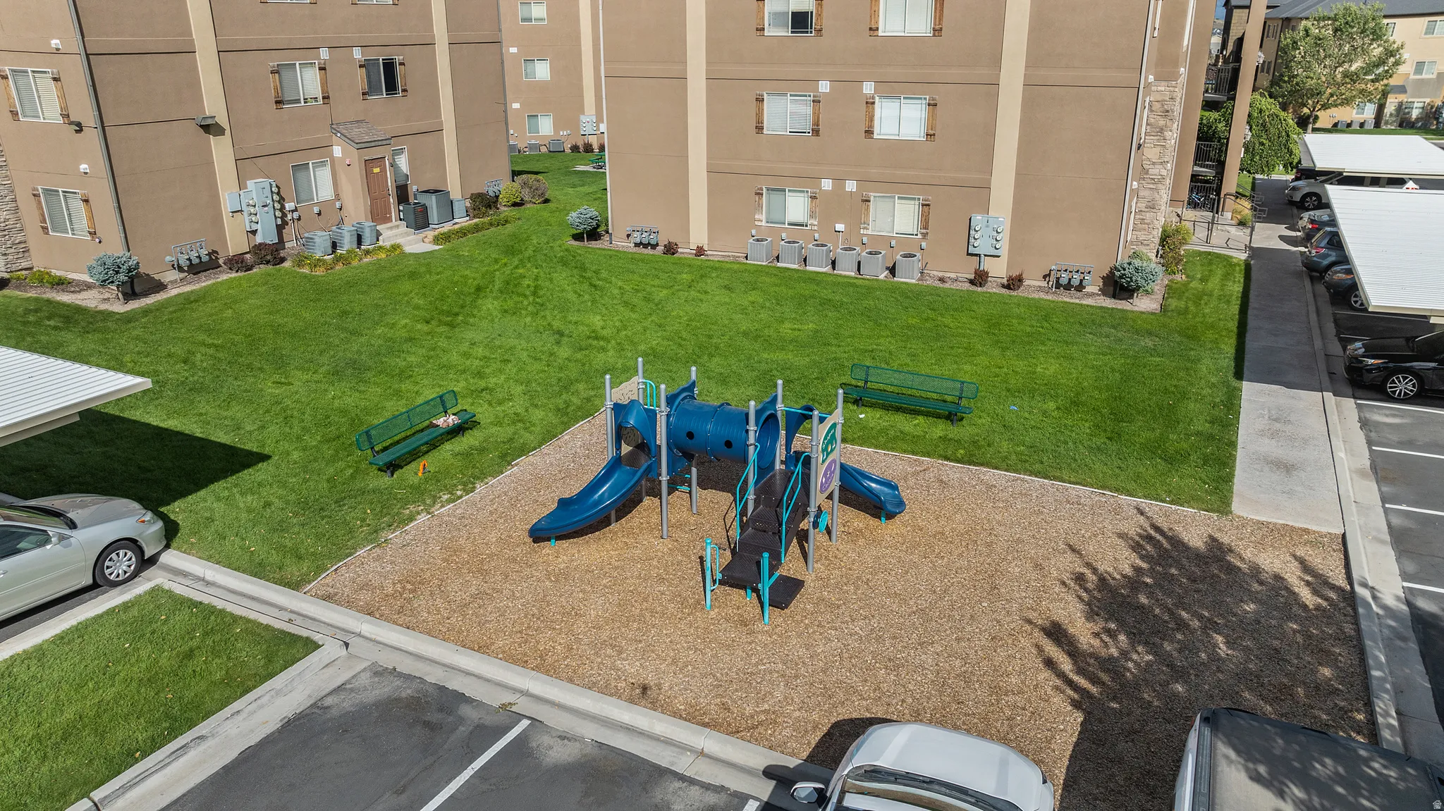 Expansive green spaces with a playground structure and dedicated covered parking
