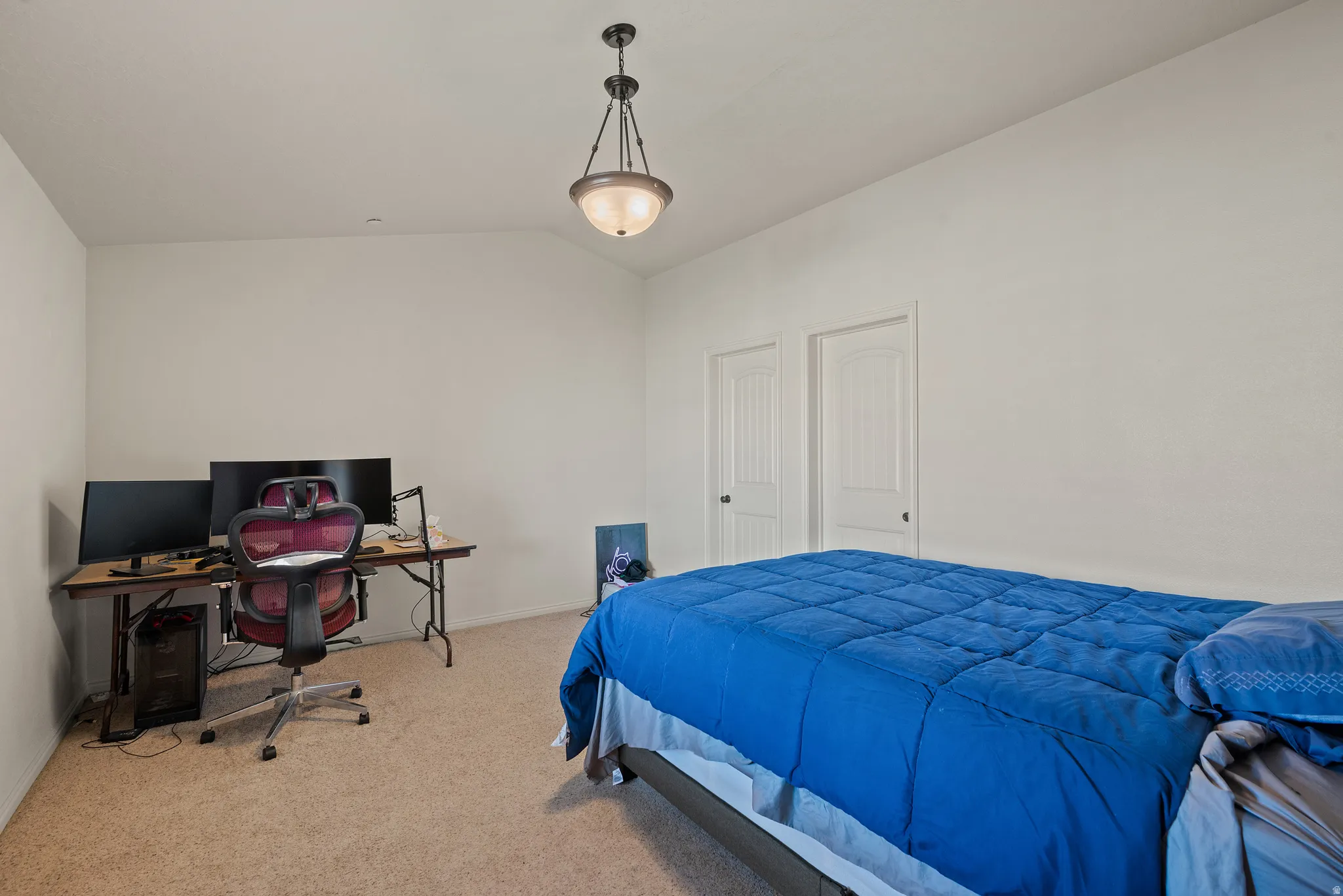 Vaulted ceiling, carpeted flooring, two paneled doors, and a decorative semi-flush mount light fixture