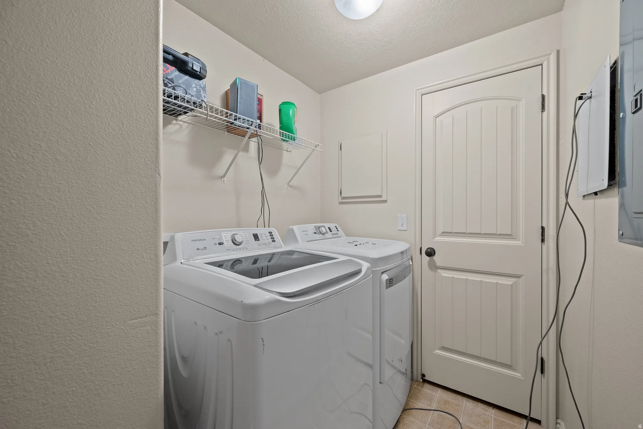 Dedicated utility space featuring a wire shelving unit, tile flooring, and a paneled door