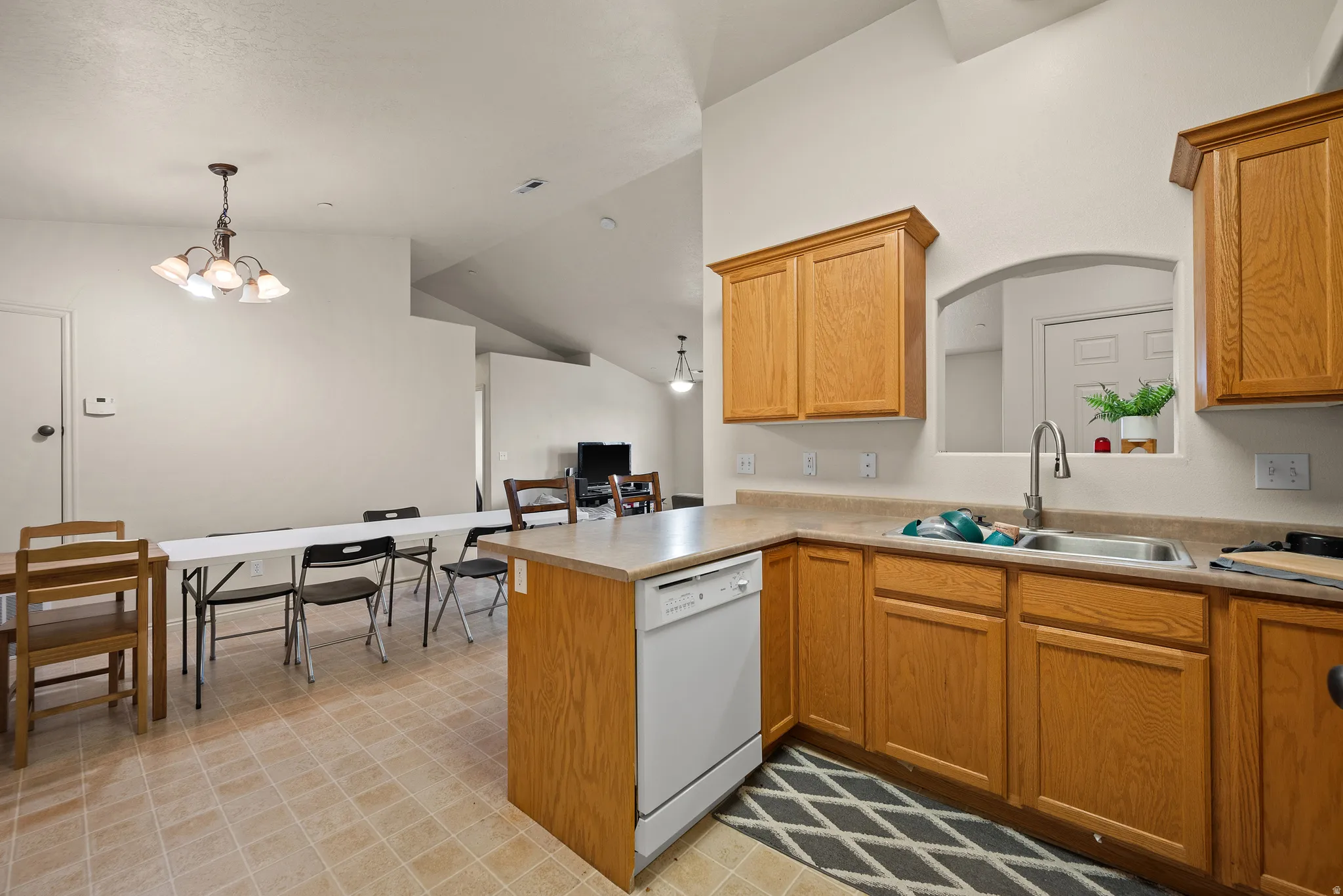 Kitchen featuring wood-finish cabinetry, a stainless steel sink with a high-arc faucet, and light-toned countertops