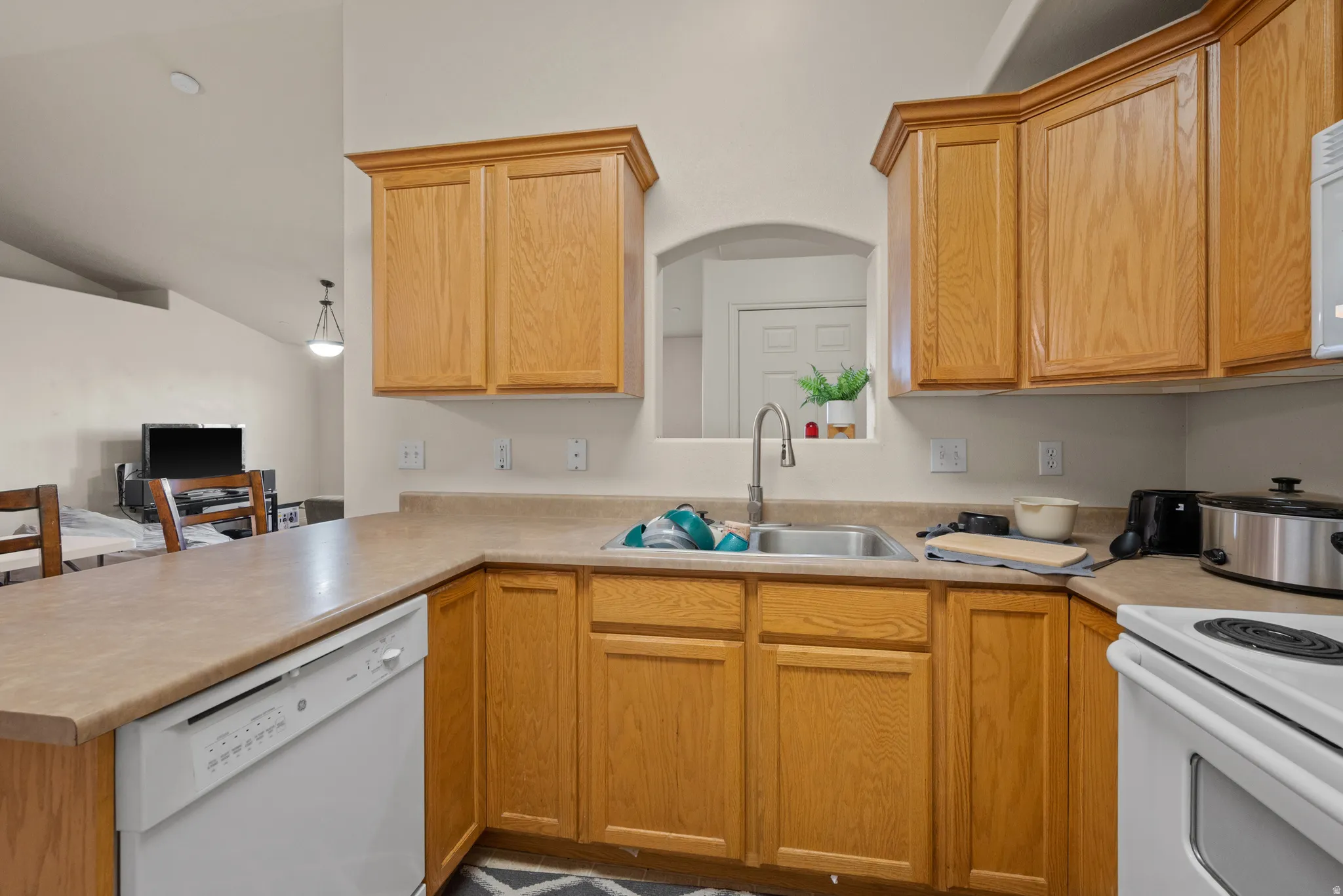 Kitchen featuring wood-finish cabinetry, a double basin stainless steel sink, and light-toned countertops