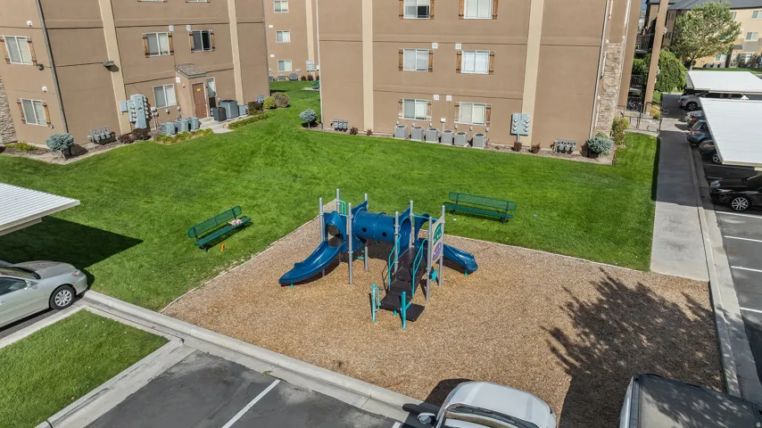 Expansive green spaces with a playground structure and dedicated covered parking