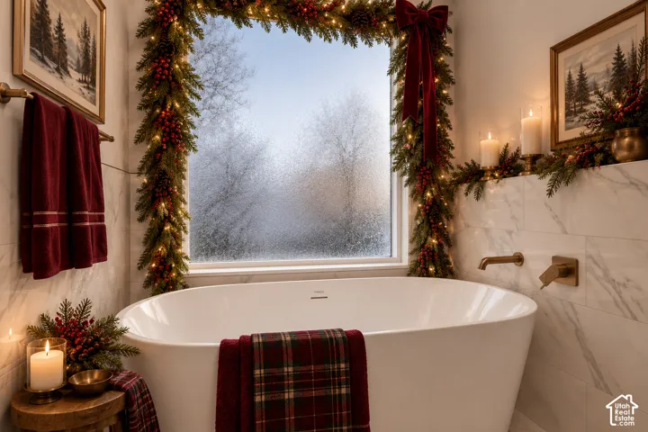 Freestanding soaking tub with a wall-mounted faucet, complemented by large format wall tiling and a prominent window