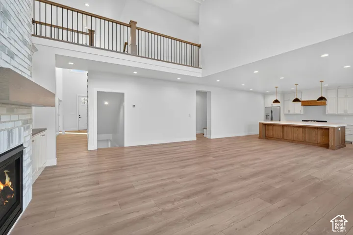 Open concept living space featuring wood-finish flooring, a white brick fireplace, a kitchen island with integrated cabinetry, and recessed lighting